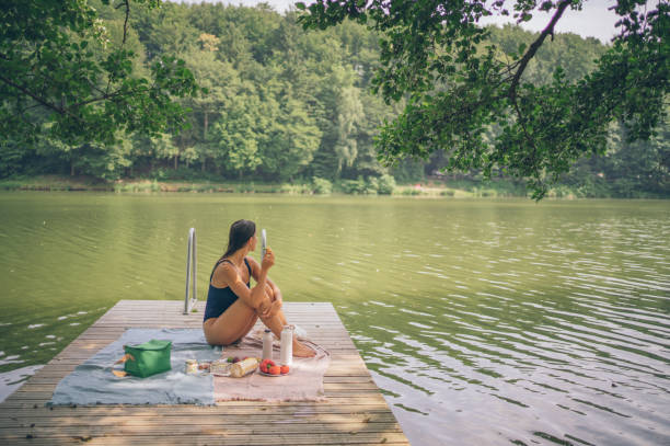 istock Young woman enjoys picnic on lakeside dock 1334201469