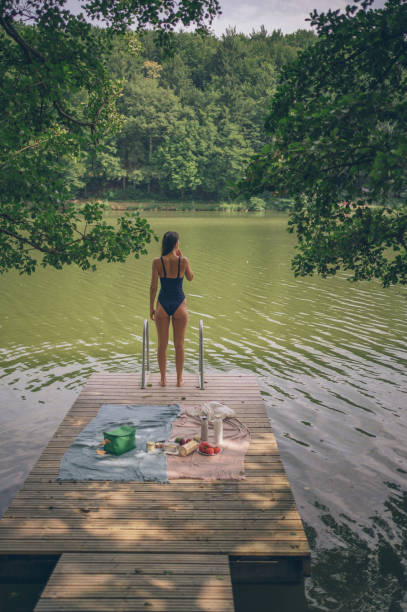 istock Young woman enjoys picnic on lakeside dock 1334201485