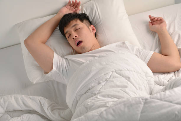 istock Young Asian man sleeping and snoring loudly lying in the bed 1334208653