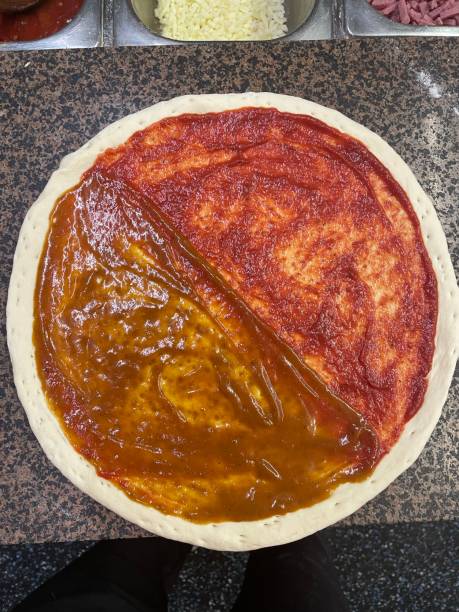 istock Pizza base with half curry and half tomato sauce base 1334210350