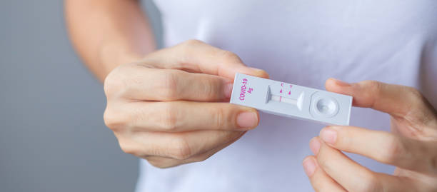 istock man holding Rapid Antigen Test kit with Negative result during swab COVID-19 testing. Coronavirus Self nasal or Home test, Lockdown and Home Isolation concept 1334213982