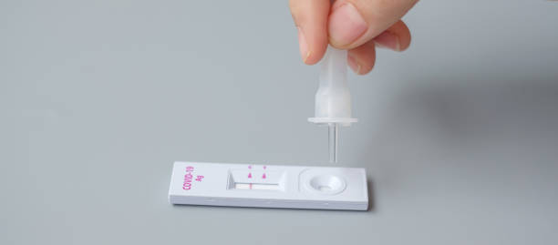 istock man swab COVID-19 testing by Rapid Antigen Test kit. Coronavirus Self nasal or Home test, Lockdown and Home Isolation concept 1334214019