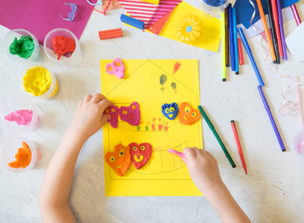 istock Child playing with modeling clay, plasticine and sculpting heart figurines. 1334224435