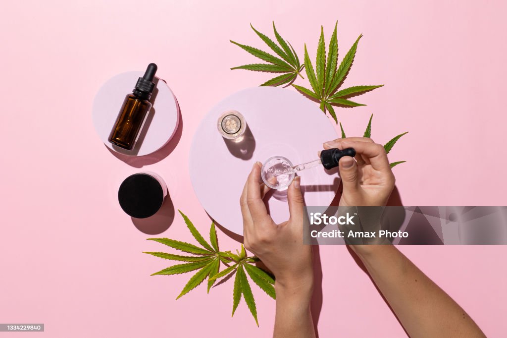 Bottles with CBD oil, THC tincture and cannabis leaves on pink background. Alternative cosmetics medical concept Cannabis Plant Stock Photo