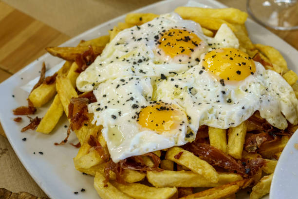 typical spanish food, fried eggs, chips and ham. scrambled eggs - smashed potatoes imagens e fotografias de stock