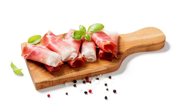 Tasty prosciutto slices Tasty prosciutto slices with basil leaves and spices isolated on white background. uncooked bacon stock pictures, royalty-free photos & images