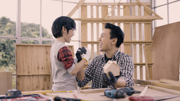 Male carpenter and his son giving high-five in workshop stock photo