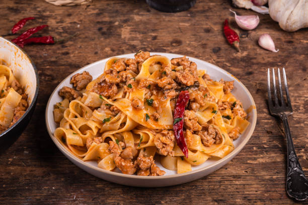 tradicional massa rústica ítalo-americana com guisado de salsicha, servido em um prato em uma mesa rústica. - fettuccine - fotografias e filmes do acervo