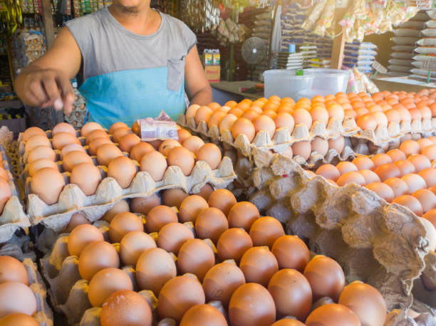 Selective focus to the Indonesian money 10,000 rupiah bill above the eggs that are sold stock photo