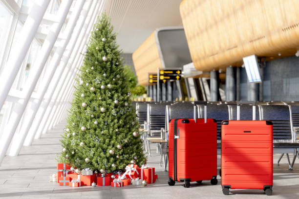 Wartebereich am Flughafen mit Gepäck in der Nähe der Sitze, Weihnachtsbaum, Ornamente, Geschenkboxen und verschwommener Hintergrund