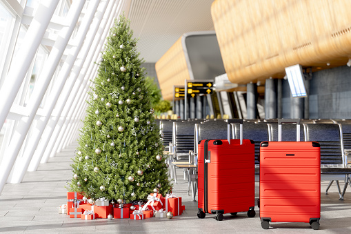 Waiting Area In Airport With Luggages Near The Seats, Christmas Tree, Ornaments, Gift Boxes And Blurred Background