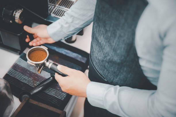 istock Barista holding pressed ground coffee making espresso with machine 1334240677