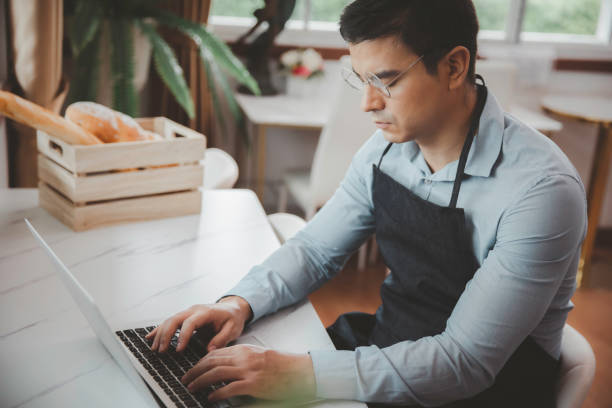 istock Entrepreneur male business owner in eyeglasses using computer laptop working seriously in coffee shop store 1334240863