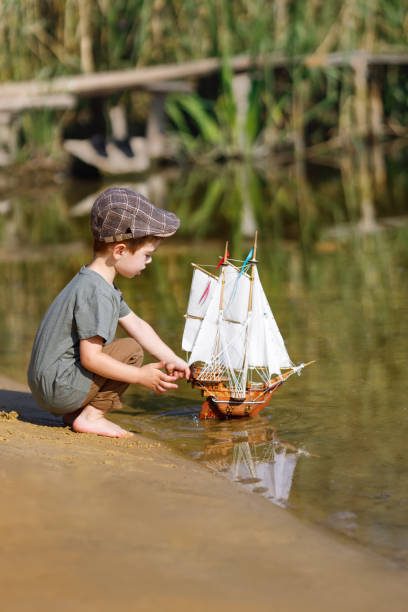 istock little boy in cap launching ship on the river 1334241444