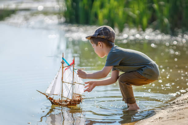 istock little boy in cap launching ship on the river 1334241445