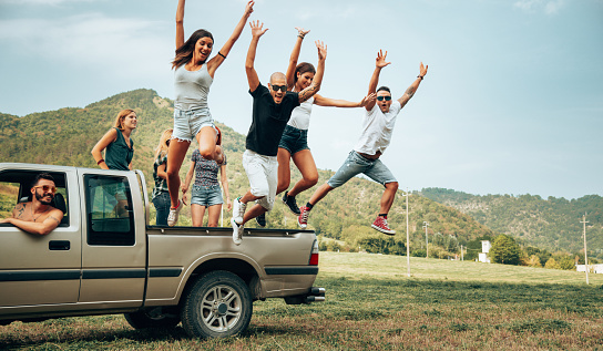 friends jumping from the car in the countryside