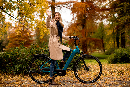Pretty young woman with electric bicycle in te autumn park
