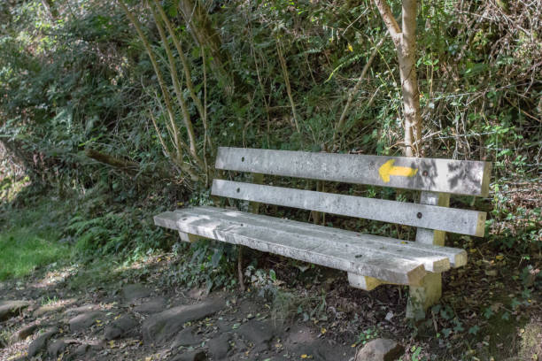 Pilgrim sign. Buen Camino. Pointer on the bench. A place for the rest of the traveler. Yellow arrow as a symbol of the pilgrims. Hiking with a backpack. Way of St. Jacob. Camino de Santiago.