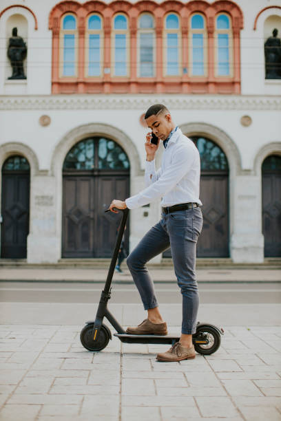 istock Young African American using mobile phone while standing with electric scooter on a street 1334247562