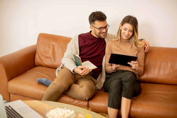 istock Young couple using digital tablet together while sitting on sofa at home 1334248635