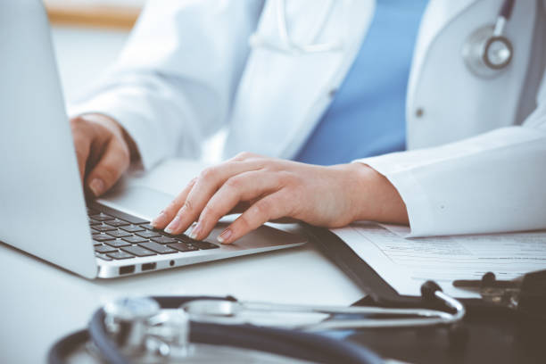 istock Unknown woman-doctor typing on laptop computer while sitting at the table. Medicine concept 1334248876