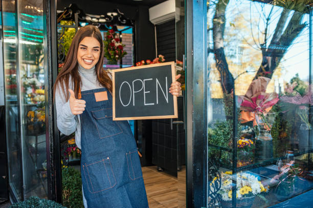 женщина приглашает в свой цветочный магазин. - owner florist sign business стоковые фото и изображения