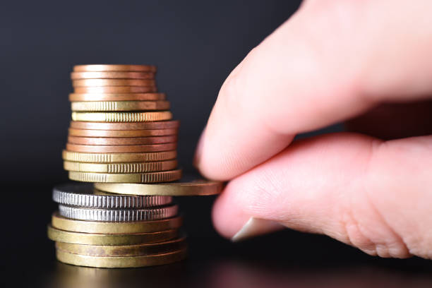 istock Hand pulls out a coin from a tower of coins on a black background 1334249698