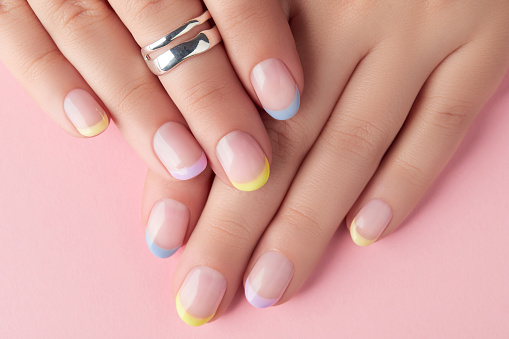 Close up manicured womans hands on pink background. Manicure, pedicure spring summer design trends