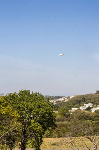 Photo of white dirigible passing through a city