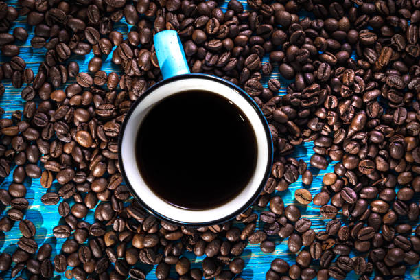 istock Black coffee in a blue mug on the table among scattered coffee beans 1334255799