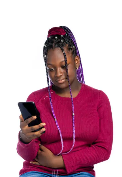 An African Teenage girl with braids reading texts on a smartphone