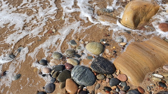 Patterns and textures of sandstone rock formations and pebbles by sea