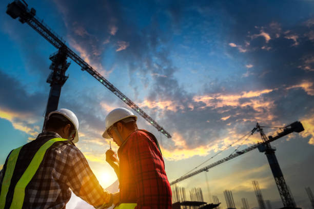 engenheiros de construção discutem com designer em canteiro de obras ou canteiro de obras de edifício highrise com plantas. - construction site - fotografias e filmes do acervo