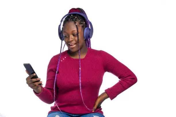 An African Teenager with a surprised look listening to music via wireless headphones connected to a smartphone