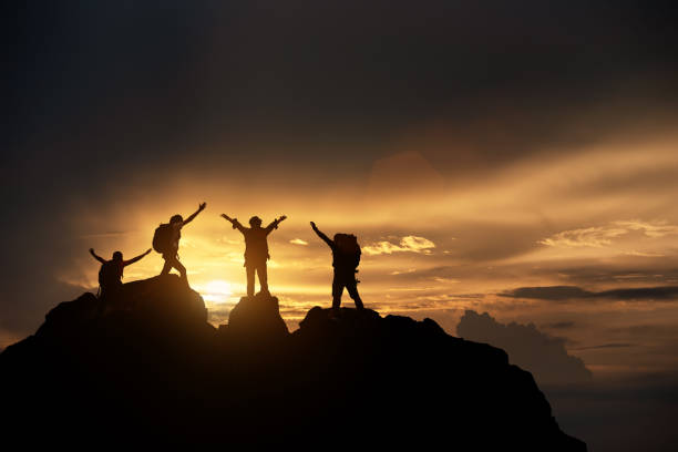 istock Silhouette of Hikers climbing up mountain cliff. Climbing group helping each other while climbing up in sunset. Concept of help and teamwork, Limits of life and Hiking success full. 1334262733