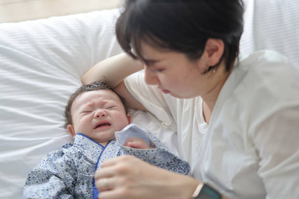 istock Mother trying to calm her crying bay on bed 1334263346