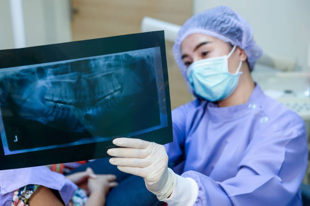 Dentist woman showing an orthodontist x-ray picture and explaining to patient in dentist's office. Focusing on  x-ray picture Dentist woman showing an orthodontist x-ray picture and explaining to patient in dentist's office. Focusing on  x-ray picture animal jaw bone stock pictures, royalty-free photos & images