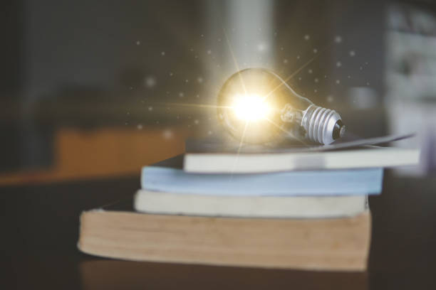 istock Glowing light bulb on a book in concept of idea innovation and inspiration. 1334267182