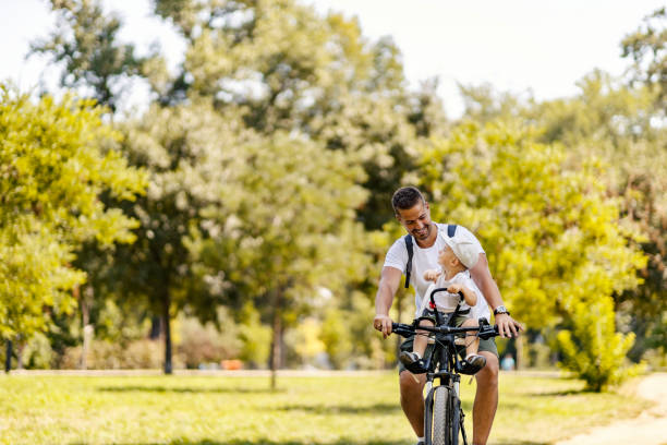 istock Dad and son ride bikes through the forest. A little boy sits in a bicycle basket while his father rides him through the woods. They talk and look each other straight in the eye. Casual day off 1334267470