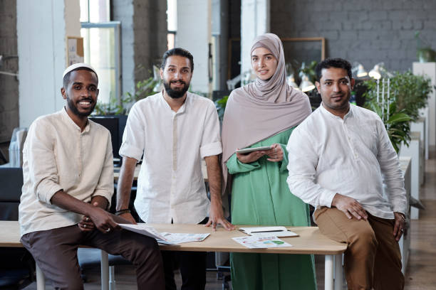 istock Four young intercultural businesspeople standing by workplace in large office 1334268725