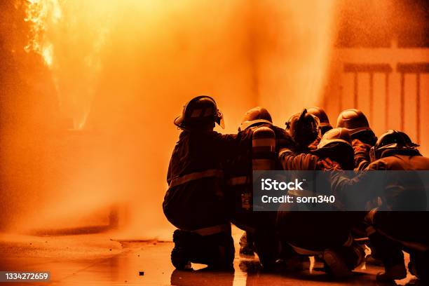 Firefighter Using Extinguisher Or Twirl Water Fog Type Fire Extinguisher To Spray Water From Hose For Fire Fighting With Fire Flame On Fuel And Control Fire For Safety In Plant Of Industrial Area Stock Photo - Download Image Now