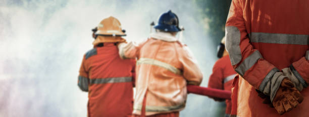 istock Firefighter chief standing in hands clasped behind the back and control to his team while preparing an extinguisher to spray water from hose for fire fighting on background, Focusing on chief. 1334272688