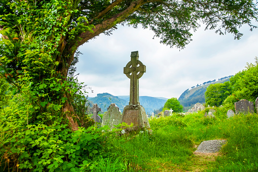 White christian stone cross in a cemetery in spring