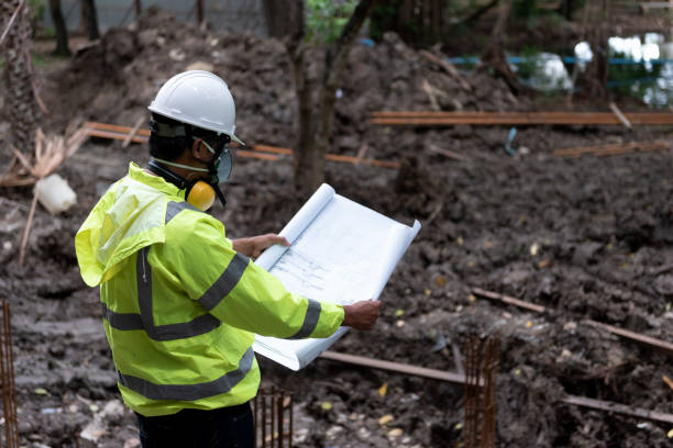 istock Civil Engineer People wearing safety helmet while inspection detail on construction site with drawing blueprint. Surveyor and checking building foundation structure on soil. 1334272814