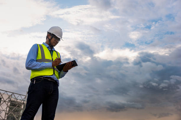 istock Engineering Consulting People on construction site holding tablet in his hand. Building inspector. Construction site checking by technology and business workflow of new building. 1334272875