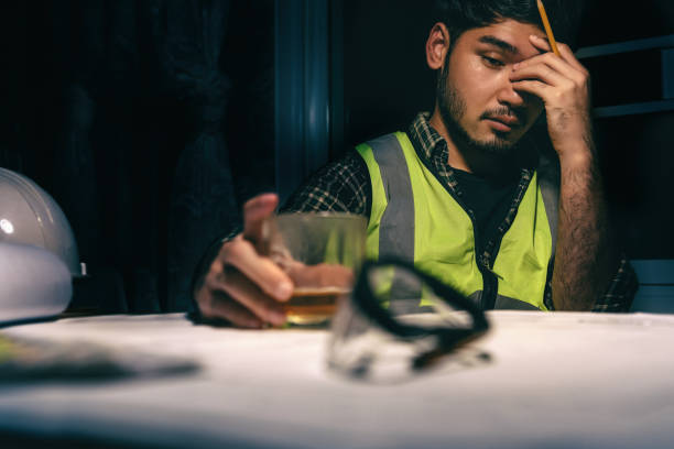 istock Engineer Designer freelance sit drinking from Stress on the desk, Planning with blueprint on desk in office at night, Economic poison, Stressed with work. 1334275009