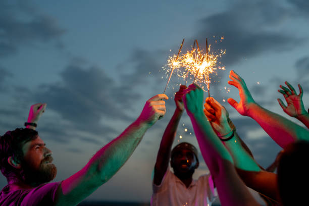 istock Two intercultural men and other people raising hands with bengal lights 1334276990