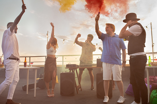 Group of cheerful multiracial people with smoke firecrackers dancing ecstatically