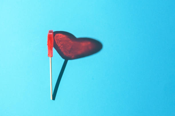 istock Lollipop in the form of a heart on a blue background with a sharp shadow. 1334278968
