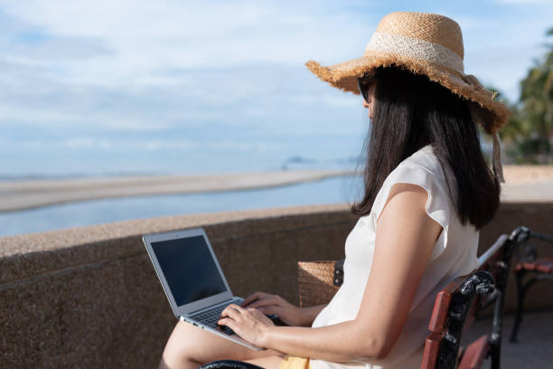 istock Unrecognizable Asian woman using laptop computer, relaxing or working at beach. 1334279117